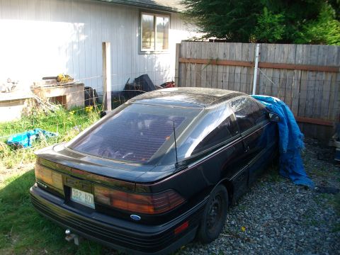 1989 Ford Probe - This 1989 Ford Probe is parked in a gravel area next to a house with a wooden fence.