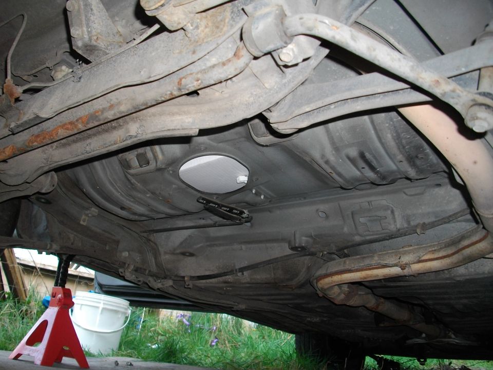 Underside of a car on jack stands, showing suspension and exhaust components