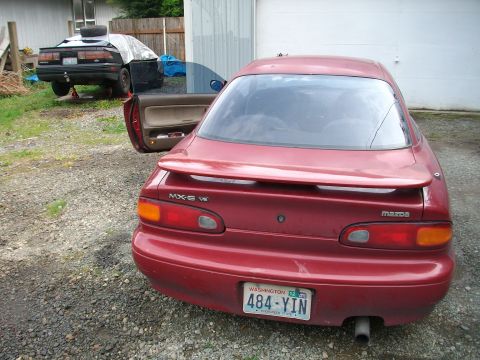 1989 Ford Probe - Rear view of a red coupe with another vehicle in the background.