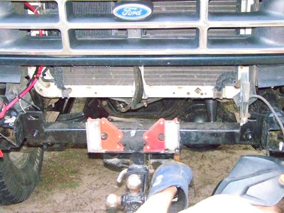 Ford grille and radiator assembly with tow hitch attached to the front bumper. Welding equipment is visible on the right
