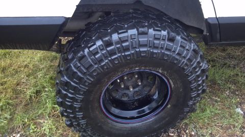 1995 Jeep Cherokee - Close-up of a vehicle's large off-road tire and wheel assembly, showing aggressive tread patterns.
