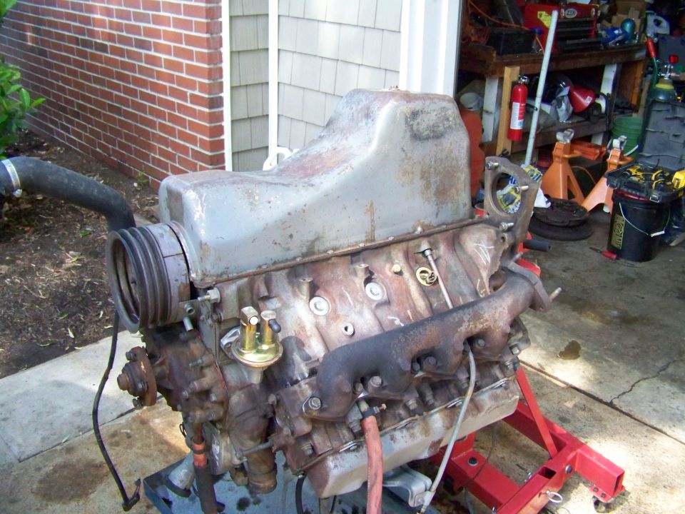 V8 engine on a red engine stand, in front of a garage