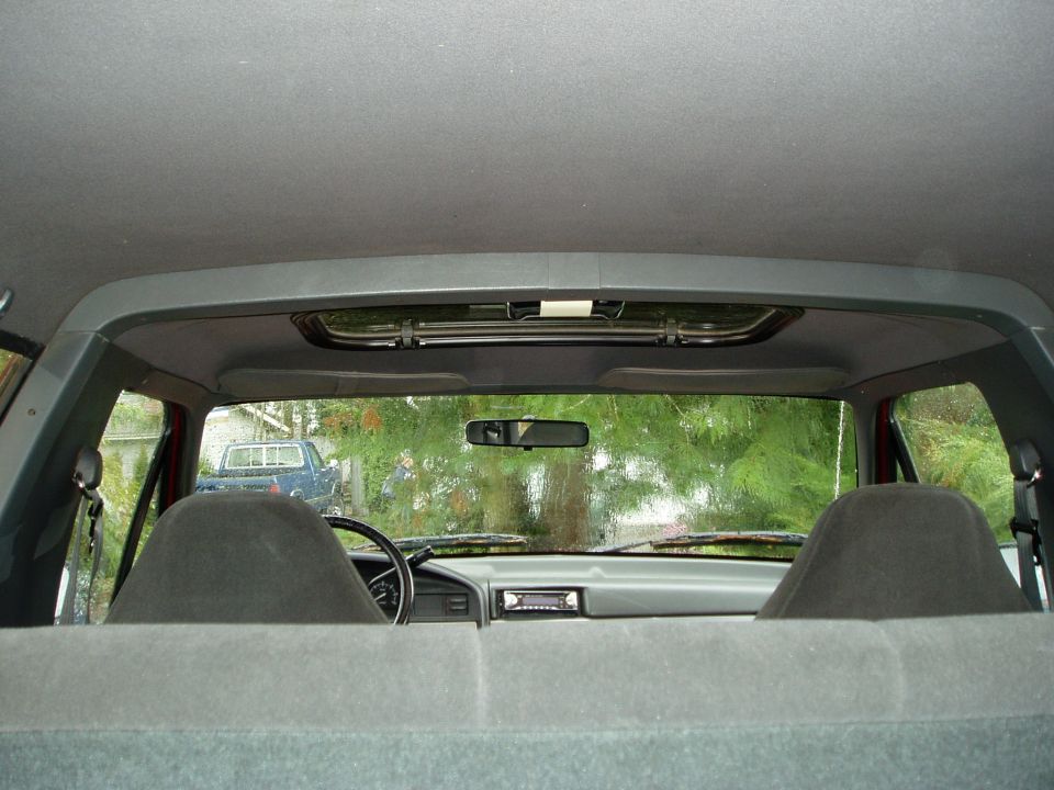 Interior view from back seat looking forward through windshield at another truck parked outside