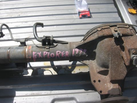 1987 Jeep Comanche - A rusty rear axle assembly, marked 'EXPLORER 1978' in pink, rests on a ribbed metal surface.