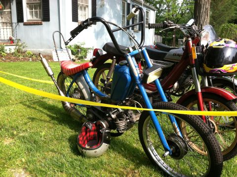 1981 Garelli Rally Sport - Two mopeds are parked on a grassy lawn in front of a house, with yellow caution tape in the foreground.