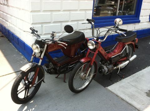 1981 Garelli Rally Sport - Two mopeds are parked next to each other on a sidewalk in front of a building.