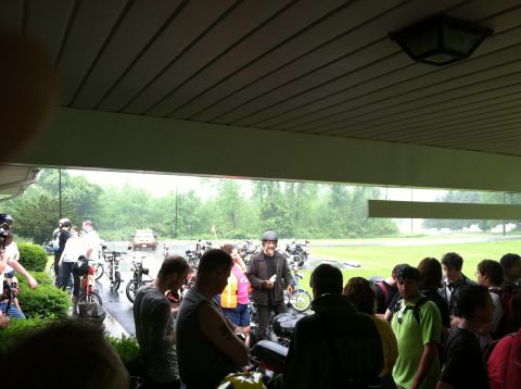 1981 Garelli Rally Sport - A group of people and motorcycles are gathered outdoors under a covered area.