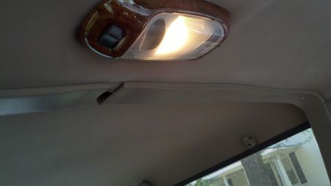 1994 Ford Bronco - The interior ceiling of a 1994 Ford Bronco shows a lit overhead console with wood trim.