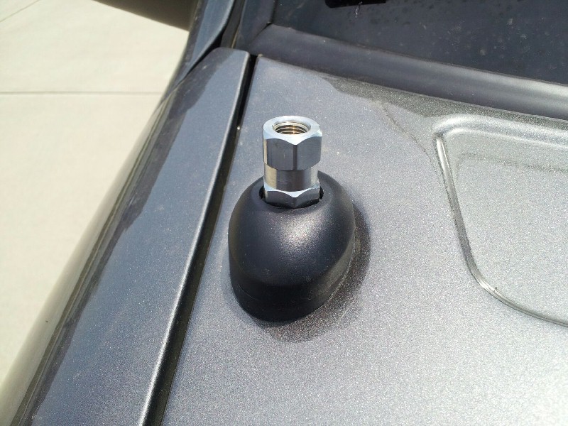 Close-up of a black antenna base with a silver nut on a gray car roof