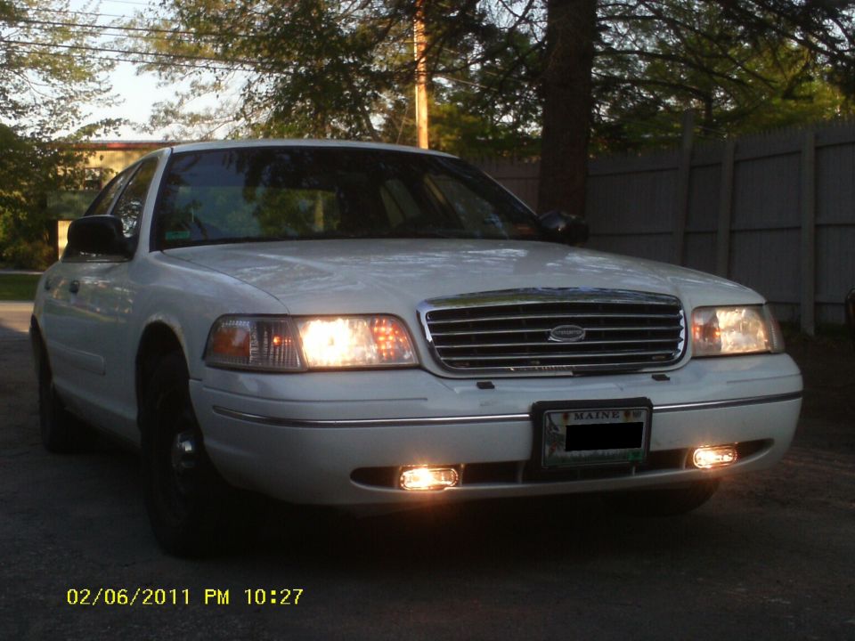 White sedan with chrome grille and headlights on. License plate reads MAINE