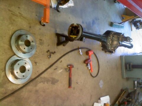 1988 Ford Bronco - Tools and automotive parts are laid out on a concrete floor, suggesting a repair or maintenance session.