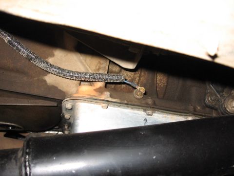 1995 Ford Bronco - Underside view of an automatic transmission with a new bright-finish pan and gasket installed, with a braided-sleeved wire running to a blu…