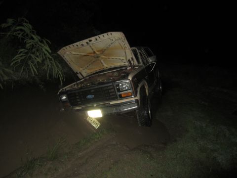 1982 Ford Bronco - Ford Bronco stuck in mud with hood open at night.