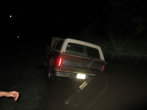 1982 Ford Bronco - A Ford Bronco is stuck in the mud at night with its hood open.