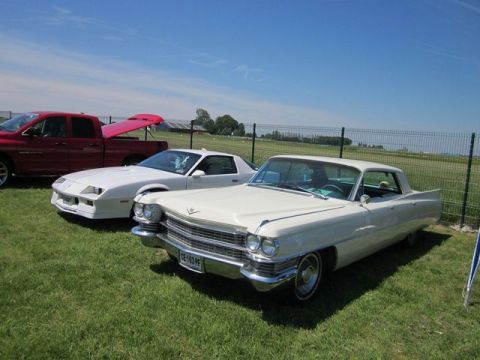 1991 Ford LTD Crown Victoria - A white 1963 Cadillac Coupe de Ville is parked on grass next to a white Camaro and a red truck.