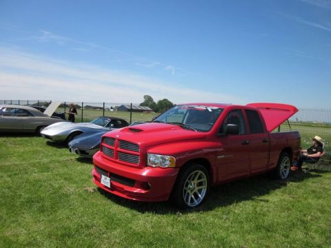 1991 Ford LTD Crown Victoria - A red Dodge Ram pickup truck is parked on a grassy field alongside other vehicles under a clear blue sky.