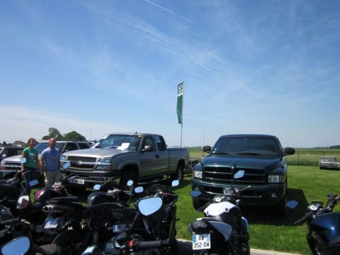 1991 Ford LTD Crown Victoria - A collection of pickup trucks and motorcycles are displayed outdoors on a sunny day.