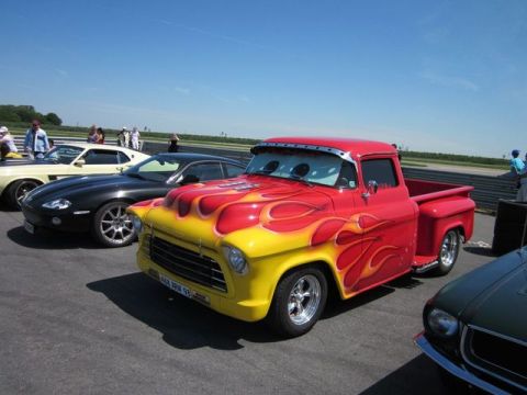 1991 Ford LTD Crown Victoria - A custom pickup truck with flame graphics is displayed at an outdoor event with other vehicles.