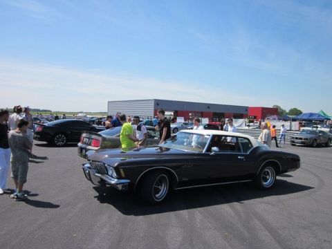 1991 Ford LTD Crown Victoria - A classic coupe with a white roof is displayed at an outdoor car show with other vehicles and attendees.