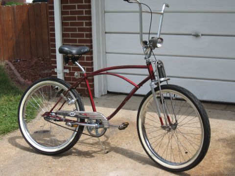 1994 Ford Bronco - A red cruiser bicycle with chrome handlebars and whitewall tires is parked in front of a garage door.