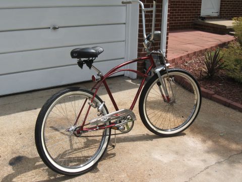 1994 Ford Bronco - A red cruiser bicycle with whitewall tires is parked on a concrete driveway in front of a garage.