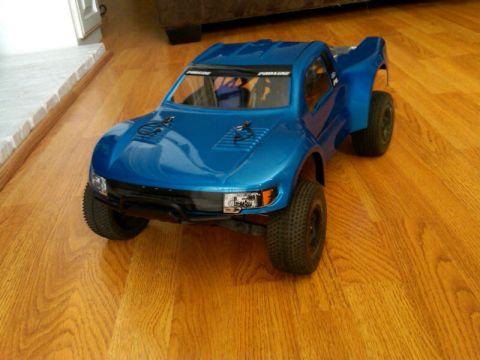 1986 Ford Bronco - RC truck with "PROLINE" text on the windshield sits on a wood floor.