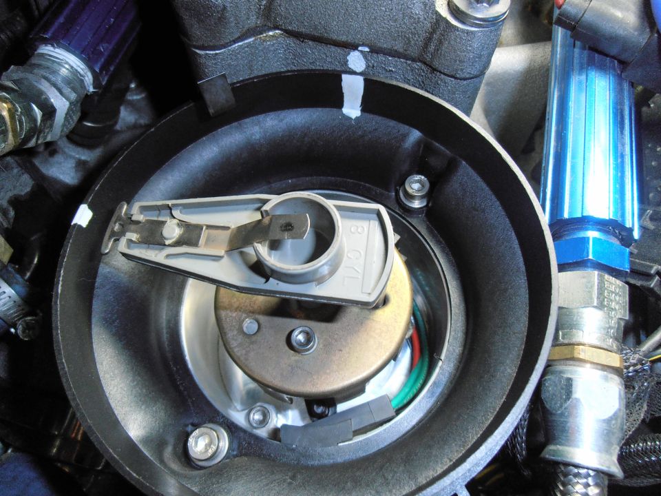 Engine ignition distributor cap removed showing rotor and reluctor inside