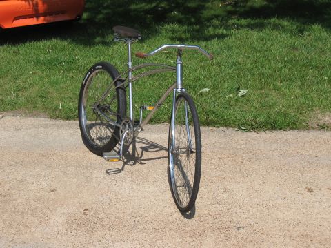 1994 Ford Bronco - A vintage-style cruiser bicycle with chrome accents and a brown saddle is parked on a paved surface next to a grassy area.