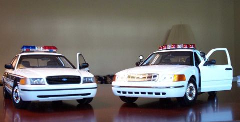 1998 Ford Crown Victoria - Two detailed models of the 1998 Ford Crown Victoria police car are displayed with their doors ajar.