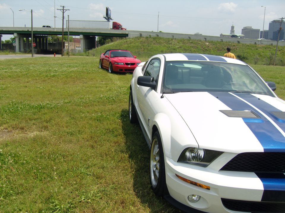 White Mustang with blue stripes parked next to a red convertible Mustang