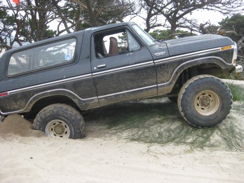 1979 Ford Bronco - This black 1979 Ford Bronco is stuck in the sand, with its front right tire partially buried.