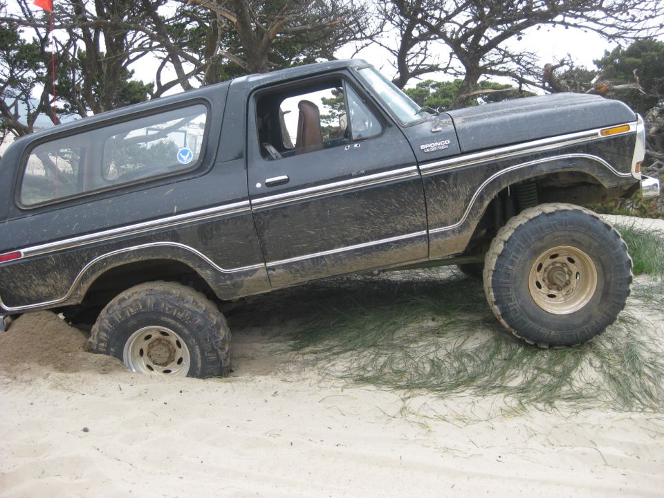 Black 1979 Ford Bronco stuck in sand, side view