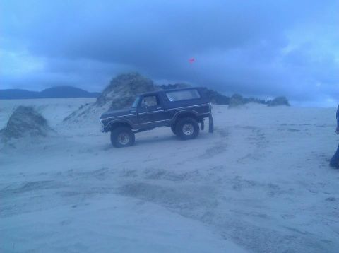 1979 Ford Bronco - Ford Bronco navigating sand dunes under a dramatic sky.