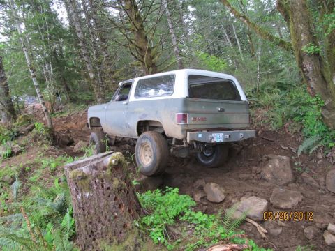 1979 Ford Bronco - A GMC K5 Blazer navigates a rocky, wooded trail on a cloudy day.