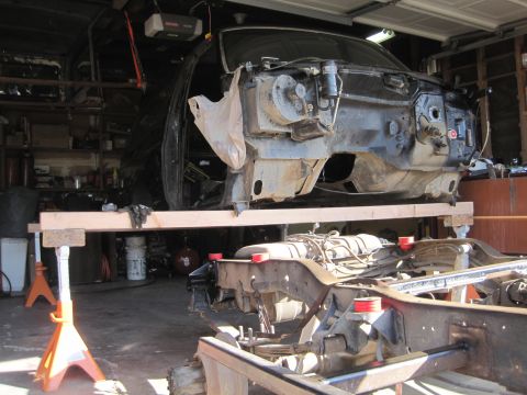 1989 Ford Bronco - The vehicle body is separated from the chassis and supported by jack stands in a garage setting.