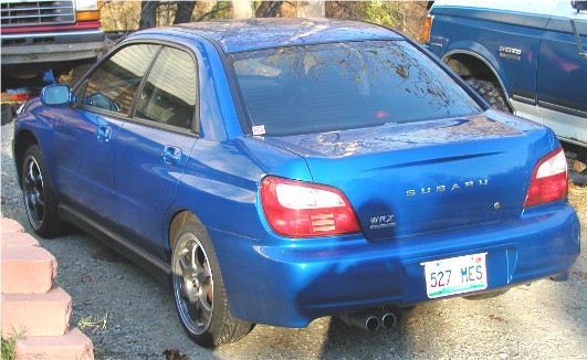 Blue Subaru WRX sedan parked next to a blue pickup truck