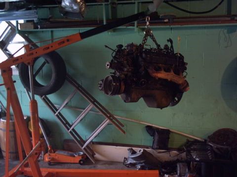 1991 Ford LTD Crown Victoria - An engine is suspended by a hoist, suggesting it has been removed from a vehicle.