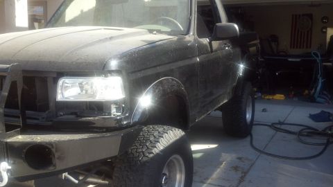 1995 Ford Bronco - This black Ford truck is parked in a garage, showing its front quarter view with modifications.