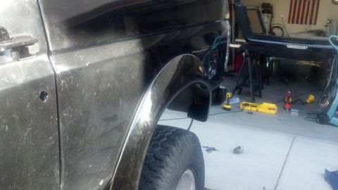1995 Ford Bronco - Side view of a black SUV undergoing repairs, with parts removed and tools scattered around.