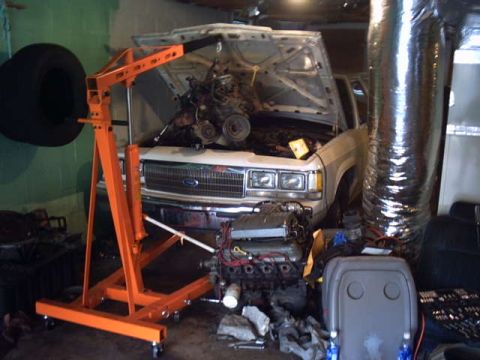 1991 Ford LTD Crown Victoria - Engine hoist positioned to remove the engine from a 1991 Ford Crown Victoria in a garage.
