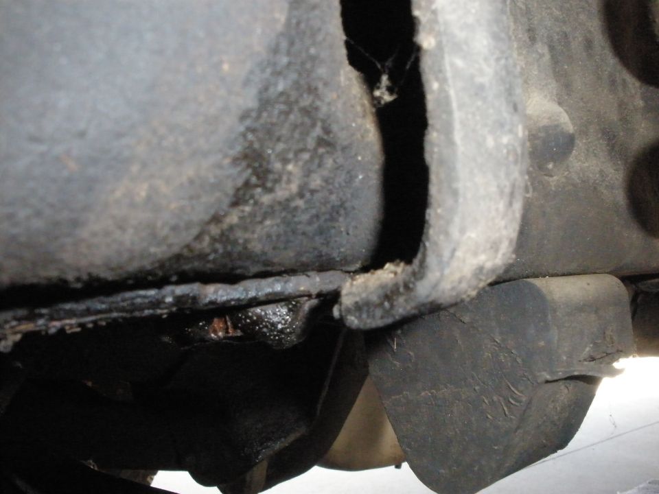 Close-up of a vehicle's frame, showing some rust and what appears to be a rubber suspension component