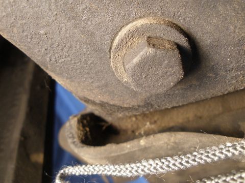 1988 Ford F-250 - A close-up view of a bolt head on a vehicle's frame, showing textured metal and a braided cord in the foreground.