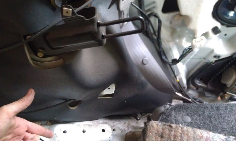 Interior view of car door panel with exposed wiring and a hand pointing