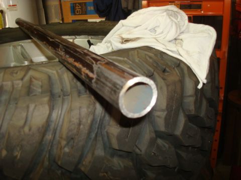 1995 Ford Bronco - A metal pipe lies across a large tire, with a white cloth draped over the tire.