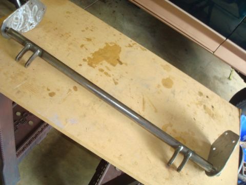 1995 Ford Bronco - A metal bar with mounting hardware is shown on a wooden surface, with a portion of a dark green and tan vehicle visible in the background.