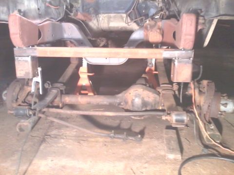 1985 Ford Bronco - The underside of a vehicle is shown, focusing on the front axle and suspension system during a repair or modification.