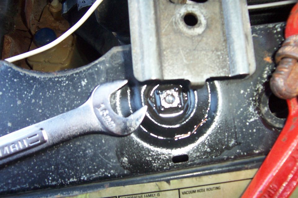 Chrome Craftsman wrench on hex bolt at black radiator support with vacuum decal below