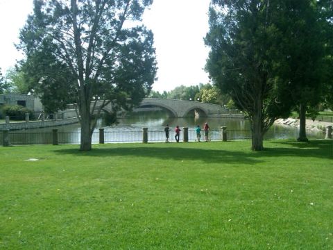 1987 Ford Bronco - A scenic park setting features a stone bridge over a body of water, with several individuals observing the view.