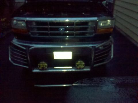 1995 Ford Bronco - The front grille and bumper of a dark-colored Ford truck are visible in this nighttime photo.
