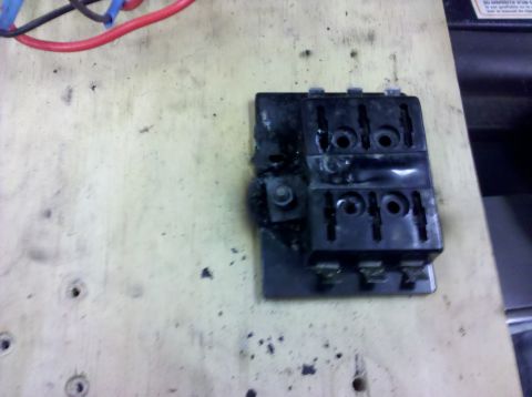 1995 Ford Bronco - A close-up view of a damaged and burnt fuse box with red and blue wires attached.